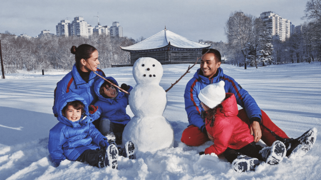 A family building a snowman during their first Canadian winter